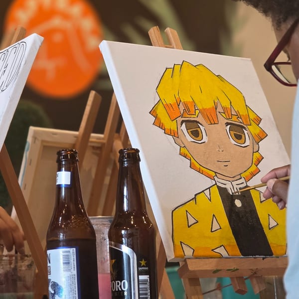 A person painting an anime character on an easel with two beer bottles nearby.