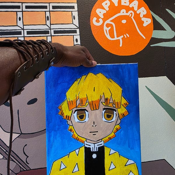 A person's arm in a leather bracer holding up a painting of an anime character with yellow hair.